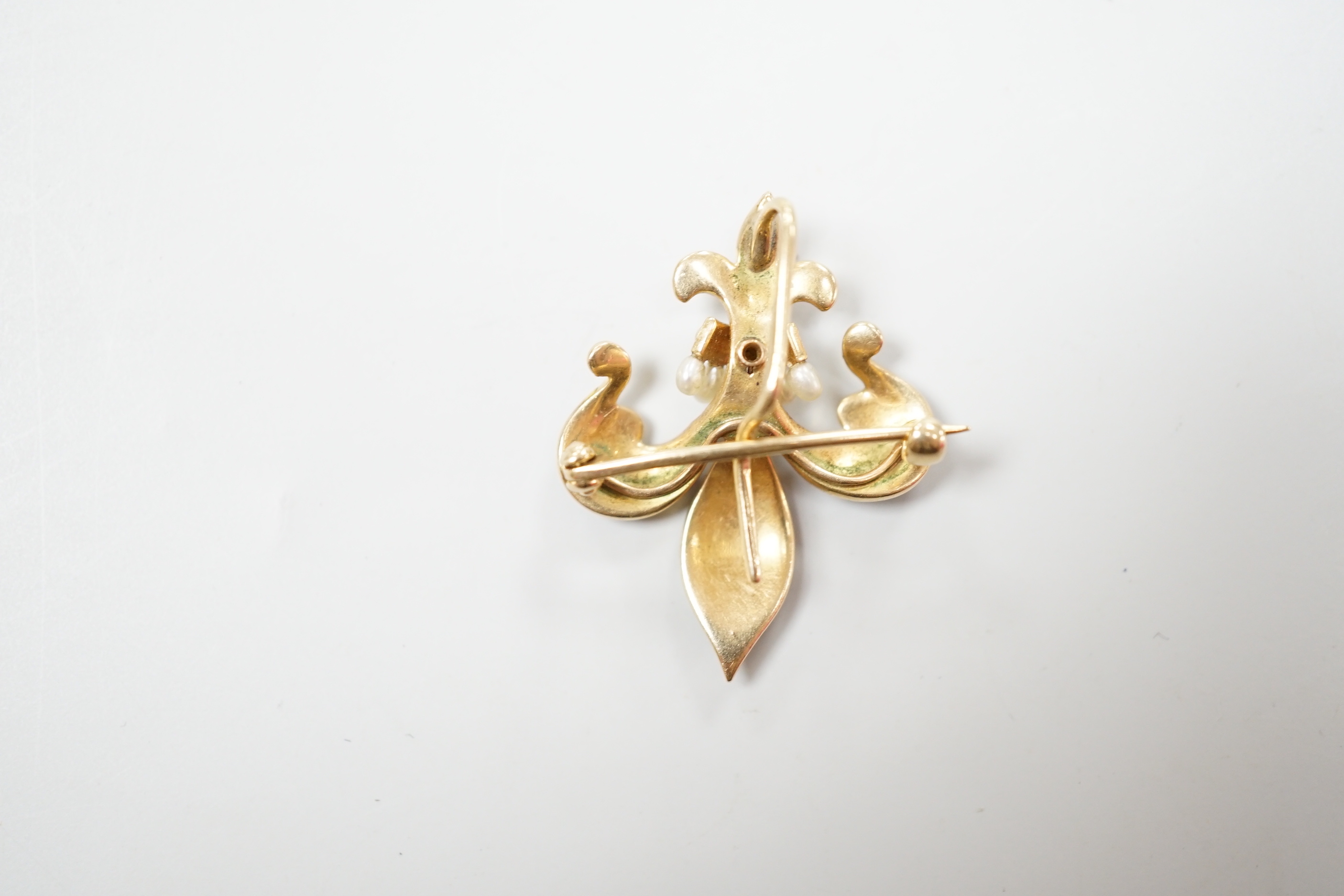 An early 20th century enamelled and pearl set gold fleur de lys brooch, the reverse with pin and suspension loop, 2.75cm., gross 3.7 grams